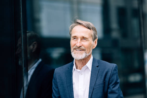 istock Smiling businessman standing outdoors at office building and looking away 1193145618