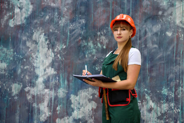 istock Woman worker in coverall with tool belt posing near grey wall 1193146473