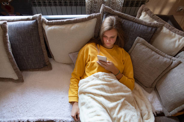 istock Young woman using mobile phone on sofa in the morning 1193148957