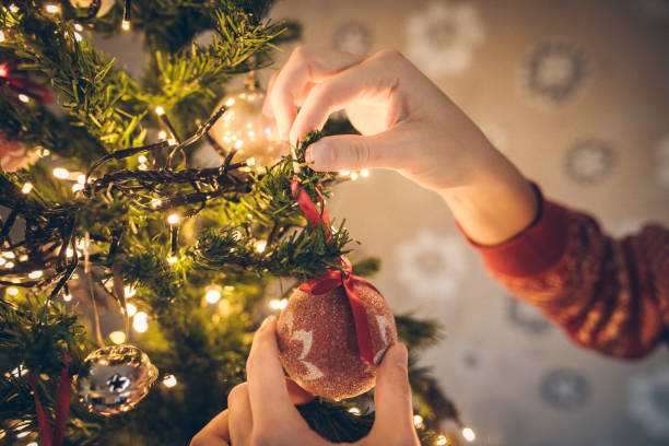 istock Young woman decorating Christmas tree in her home. Hands close up 1193149428