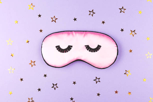 Cute pink sleeping mask on purple background.
