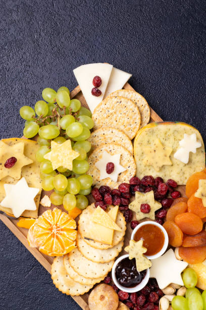 istock Assorted cheeses on wooden board plate hard cheese slices, walnuts, grapes, crackers, chutney mango, jam, dark background, top view. Copy space. 1193150948