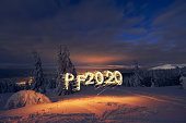 PF 2020 new year symbol lighted with sparklers in snow forest