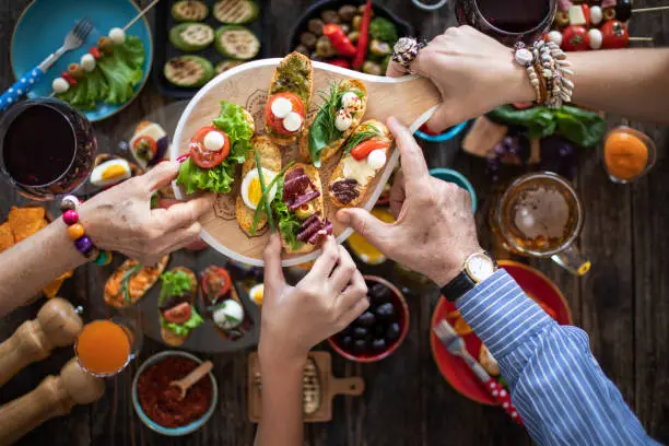 Top view of hands at the dinner table with lots of tapas