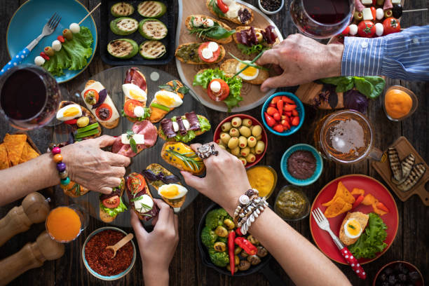 Tapas offering at the family celebration dinner with wine and beer. Top view of hands at the dinner table with lots of tapas tapas photos stock pictures, royalty-free photos & images