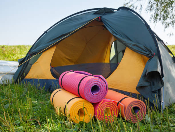 Open tent and rolled sleeping pads. Open tent and rolled sleeping pads. Campsite. beach mat stock pictures, royalty-free photos & images