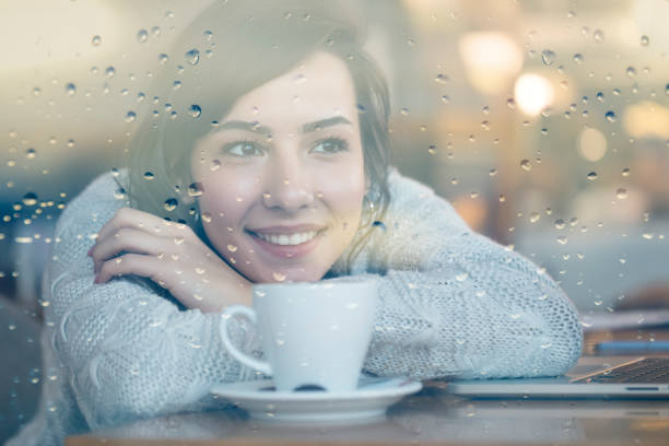 istock Happy Woman looking through window on a rainy day 1193161056