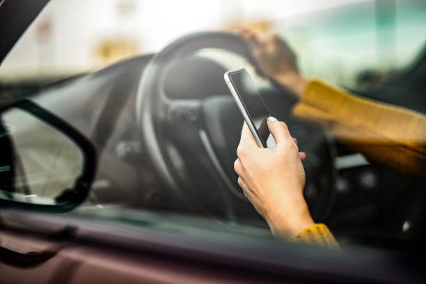 fin de main vers le haut de la femme textant un message sur le téléphone tout en conduisant une voiture. - driving text messaging accident car photos et images de collection
