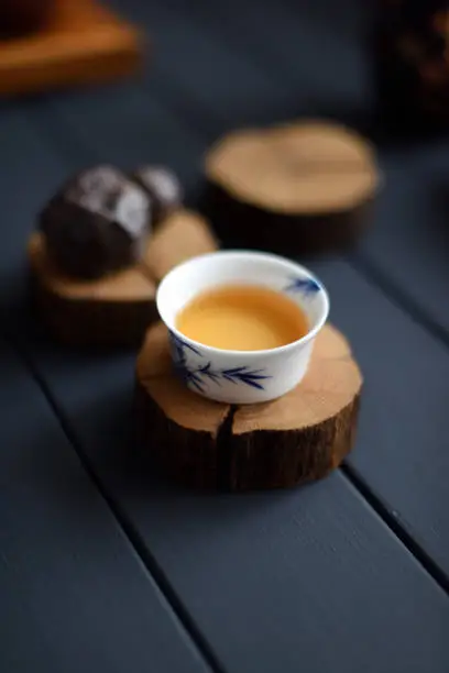 Wabi sabi concept. Black stone and green tea in porcelain cup on wood slabs on black background at tea ceremony copy space