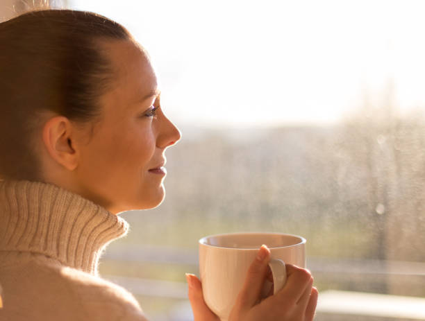 istock Girl with cup of coffee beside window 1193168821