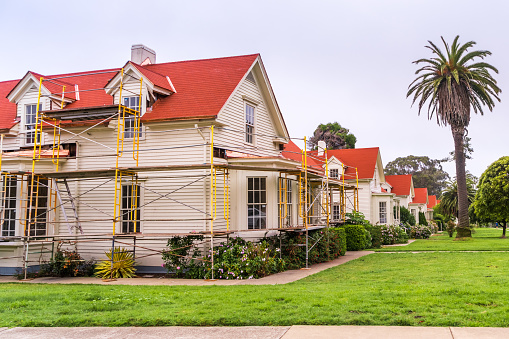 Street view of identical houses in Presidio of San Francisco, California; renovation works underway at one of the buildings