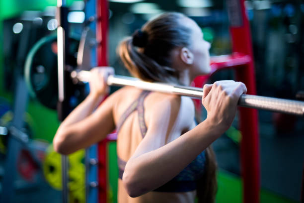 istock athlete holds the bar on her shoulders, doing squats. 1193174007