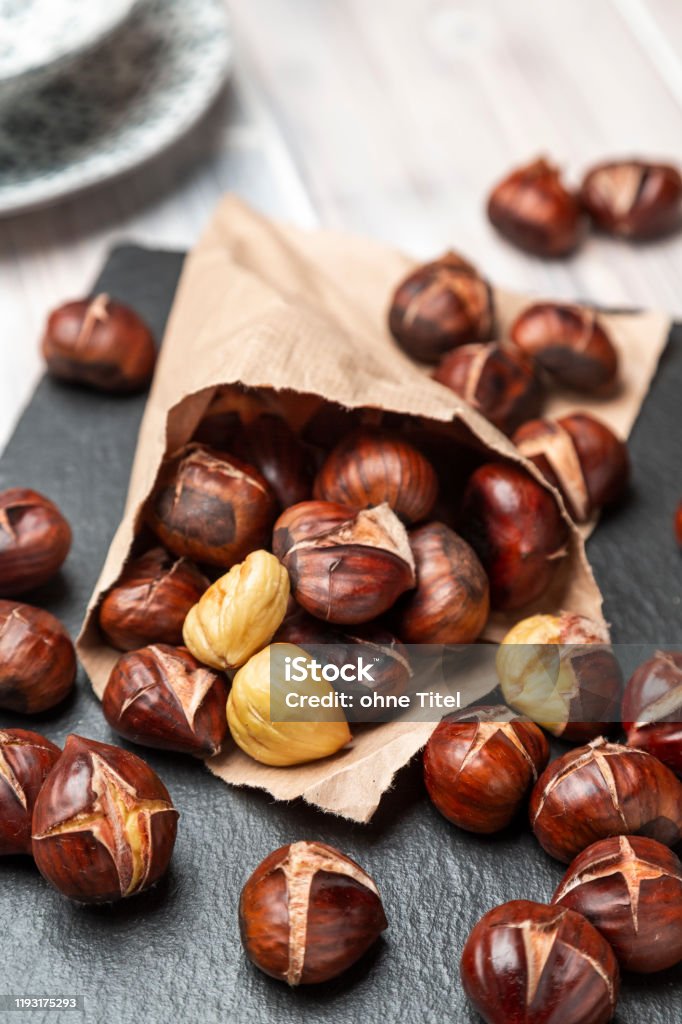 Roasted Chestnuts Roasted chestnuts in a paper bag, lying on a slate Roasted Chestnut Stock Photo