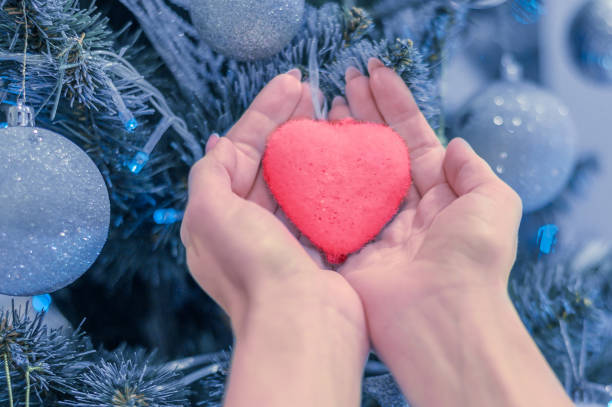 istock female hands hold heart on christmas tree 1193182523