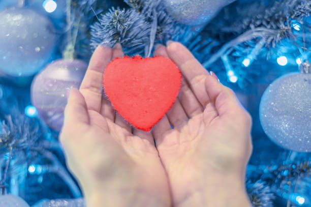 istock female hands hold heart on christmas tree 1193182524