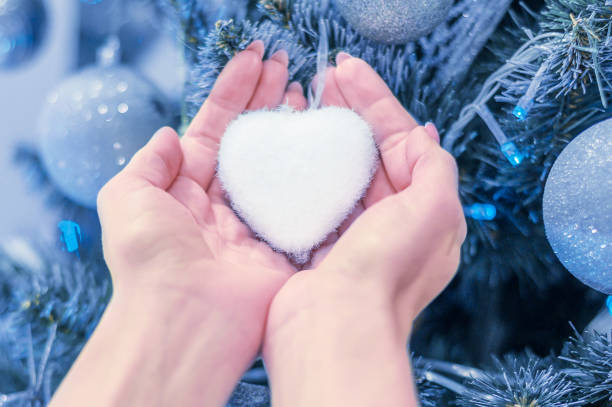 istock female hands hold heart on christmas tree 1193182562