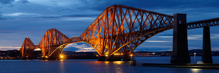The spectacular Forth Bridge, near Edinburgh, Scotland at night.  Panoramic image shot at dusk.  The bridge was completed in 1890 and designed in a cantilever design.  Crossing the Firth of Forth, it is 2467 metres long and at the time of construction, had the worlds longest single cantilever bridge span.