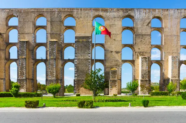 Photo of Amoreira Aqueduct and flag of Portugal in Elvas. Alentejo, Portugal.