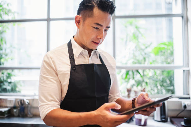 istock Chinese male barista using digital tablet at work 1193198693