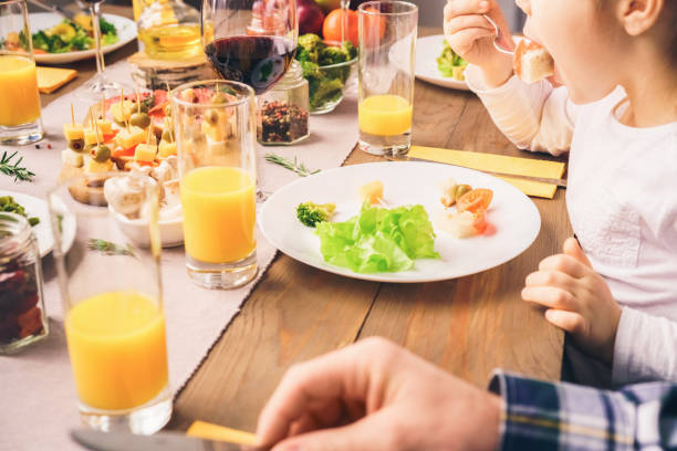 istock Little girl eats at a table with her family 1193199558