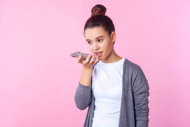 wirtualny asystent. portret nastoletniej brunetki rozmawiającej z telefonem za pomocą cyfrowej aplikacji głosowej. studio nakręcone wyizolowane na różowym tle - telephone child isolated on white elegance zdjęcia i obrazy z banku zdjęć