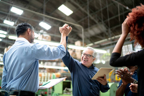 coworkers celebrating some good news in a factory - teamwork business success leadership imagens e fotografias de stock