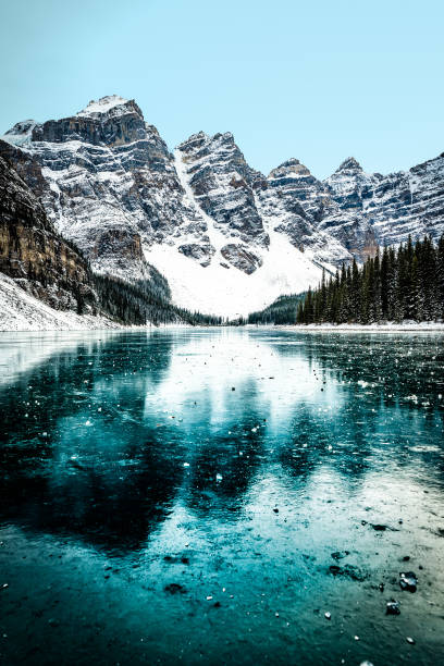 panorama de lac moraine en hiver avec l'eau gelée et les montagnes couvertes de neige, parc national de banff, alberta, canada - vertical scenics ice canada photos et images de collection