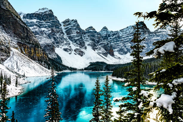 Moraine lake panorama in winter with frozen water and snow covered mountains, Banff National Park, Alberta, Canada Panorama view of Moraine Lake in Banff National Park, Alberta, Canada during winter with frozen water banff national park photos stock pictures, royalty-free photos & images