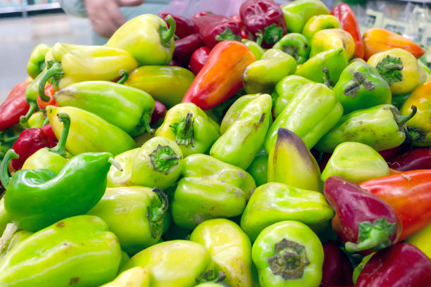 pimientos rojos y amarillos en un mostrador de supermercado. - green bell pepper bell pepper red bell pepper groceries fotografías e imágenes de stock