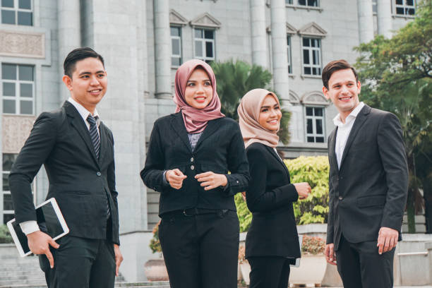 A group of smart asian career men and women gather outside the office building looking professional and modern. stock photo