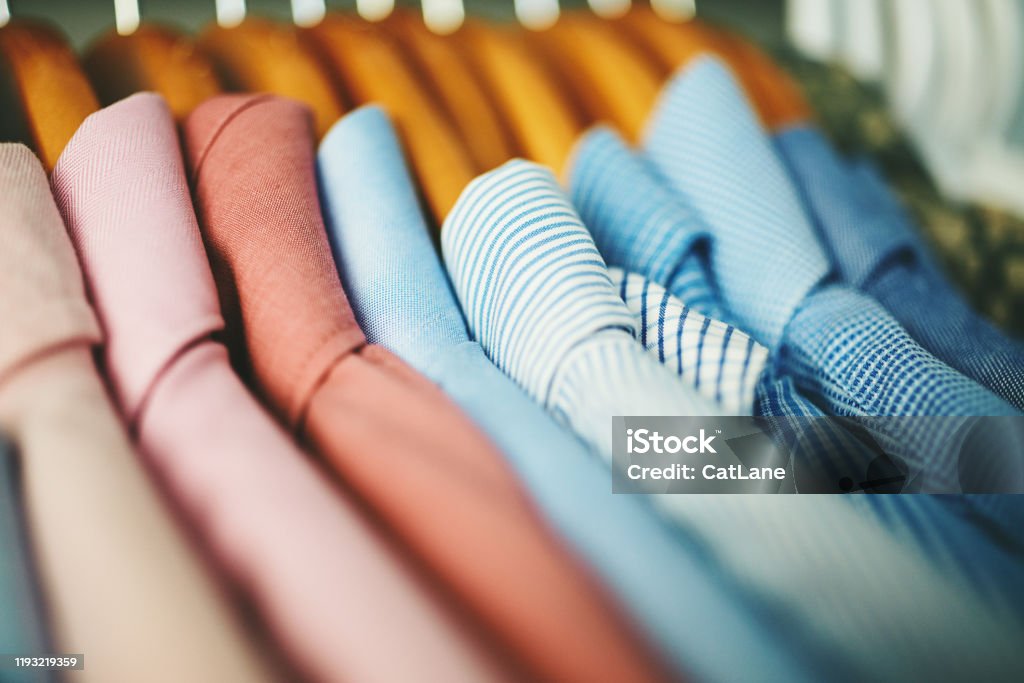 Assortment of mens shirts on wooden coat hangers Assortment of mens shirts hanging on wooden coat hangers in a walk in closet Clothing Stock Photo