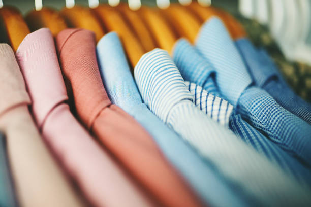 Assortment of mens shirts on wooden coat hangers Assortment of mens shirts hanging on wooden coat hangers in a walk in closet businesswear stock pictures, royalty-free photos & images