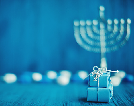 Defocused Hanukkah background with menorah, gifts and dreidel in blue setting