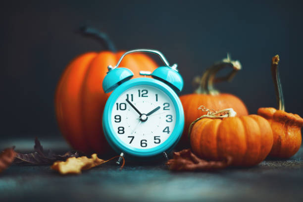 c'est l'heure de l'automne. réveil de sarcelle avec des feuilles et des citrouilles - clock time alarm clock orange photos et images de collection