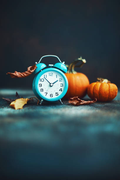 istock Time for Fall. Teal alarm clock with leaves and Pumpkins 1193220921