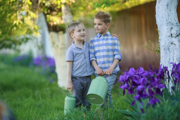 мальчики 6-7 лет на заднем дворе против деревянного забора в саду - 6 7 years lifestyles nature horizontal стоковые фото и изображения