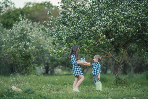 un niño y una niña de 7 a 10 años en el verano con ropa rústica caminando por el jardín - 7 10 years fotografías e imágenes de stock