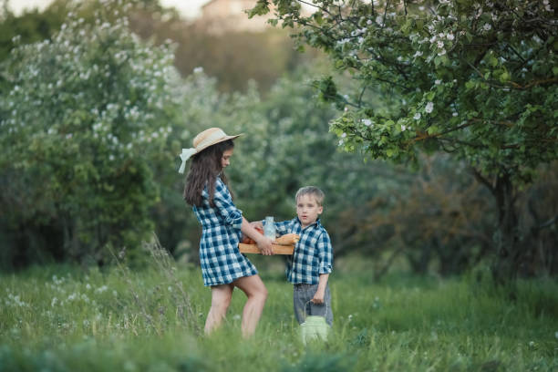 un niño y una niña de 7 a 10 años en el verano con ropa rústica caminando por el jardín - 7 10 years fotografías e imágenes de stock