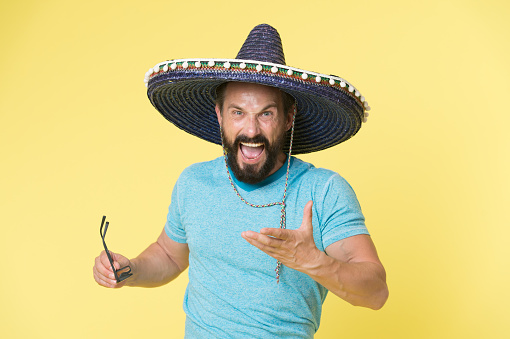 Hot tempered people. Man shouting face in sombrero hat yellow background. Guy with beard looks annoyed or angry in sombrero. Traditional rules of behaviour and manners. Man annoyed behaviour shout.
