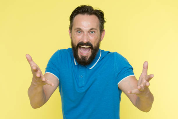 What are you doing. Stop annoying him. Overwhelmed with emotions. Handsome shouting mature man screaming standing against yellow background. Man bearded irritated annoyed can not keep calm anymore.