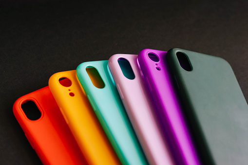 Yellow, red, purple, lilac, green, mint cases for the smartphone on the black background. Protective silicone cases for smartphone. Set of colored silicone covers for smartphone. Selective focus.