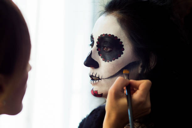 Halloween. Make-up artist making woman up as skeleton for Mexican Day of Dead Make-up artist drawing a scary makeup on the face of a brunette woman for a Halloween party halloween face paint stock pictures, royalty-free photos & images