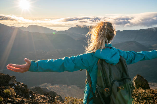 młoda kobieta na szczycie wulkanu broni wyciągnięte- wschód słońca - haleakala national park maui nature volcano zdjęcia i obrazy z banku zdjęć