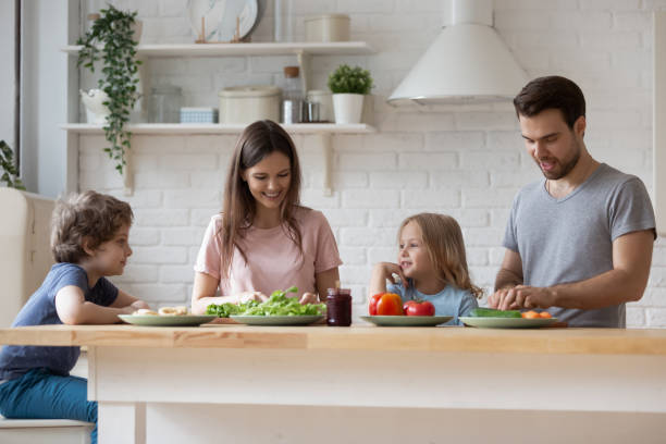 istock Happy parents with son and daughter preparing dinner, chatting 1193245303
