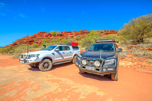 Finke Gorge National Park, Northern Territory, Australia - Aug 19, 2019: perspective view of two full 4X4 vehicles at Palm Valley in Central Australia Outback. Discovery and adventure travel concept.
