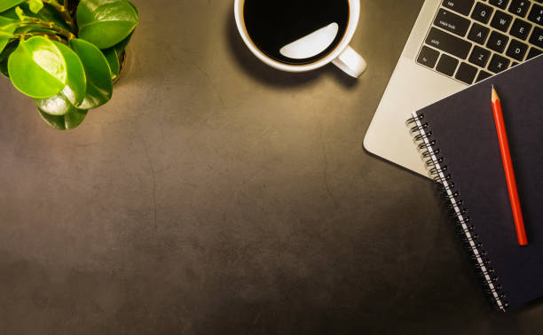 istock Top view of Workspace office desk, Black top table with laptop notebook, pencil and white cup of black coffee. Flat lay with copy space. 1193250329