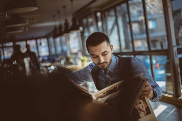 istock Businessman reading newspaper in coffee shop 1193250945