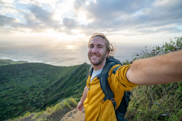istock Young man hiking at sunrise taking selfie 1193251032