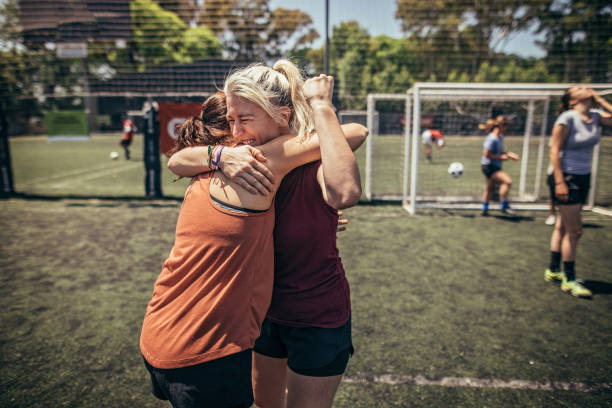 Female soccer players hugging on soccer field Group of women, female soccer players together outdoors on soccer field, two women hugging. football player girlfriend stock pictures, royalty-free photos & images