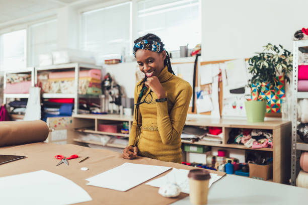 Young entrepreneur african woman, or fashion designer working in atelier Young entrepreneur african woman, or fashion designer working in atelier atelier fashion stock pictures, royalty-free photos & images